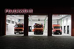 FFW Gädheim-Ottendorf Einfahrt der Feuerwehrwache mit offenen Toren und geparkten Feuerwehreinsatzwagen.